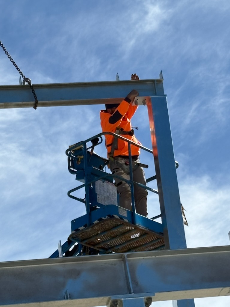Rigger positioning portal frame steel on a warehouse project